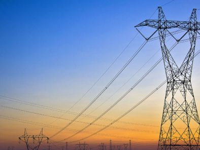 Tall power lines against a sunset sky with a gradient of blue to orange.