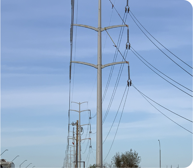 Tall utility poles with multiple power lines stretch into the distance against a blue sky.