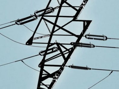 Silhouette of a power line structure resembling a lightning bolt against a clear sky.