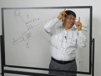 A person is standing behind a transparent board with mathematical equations, gesturing with both hands.